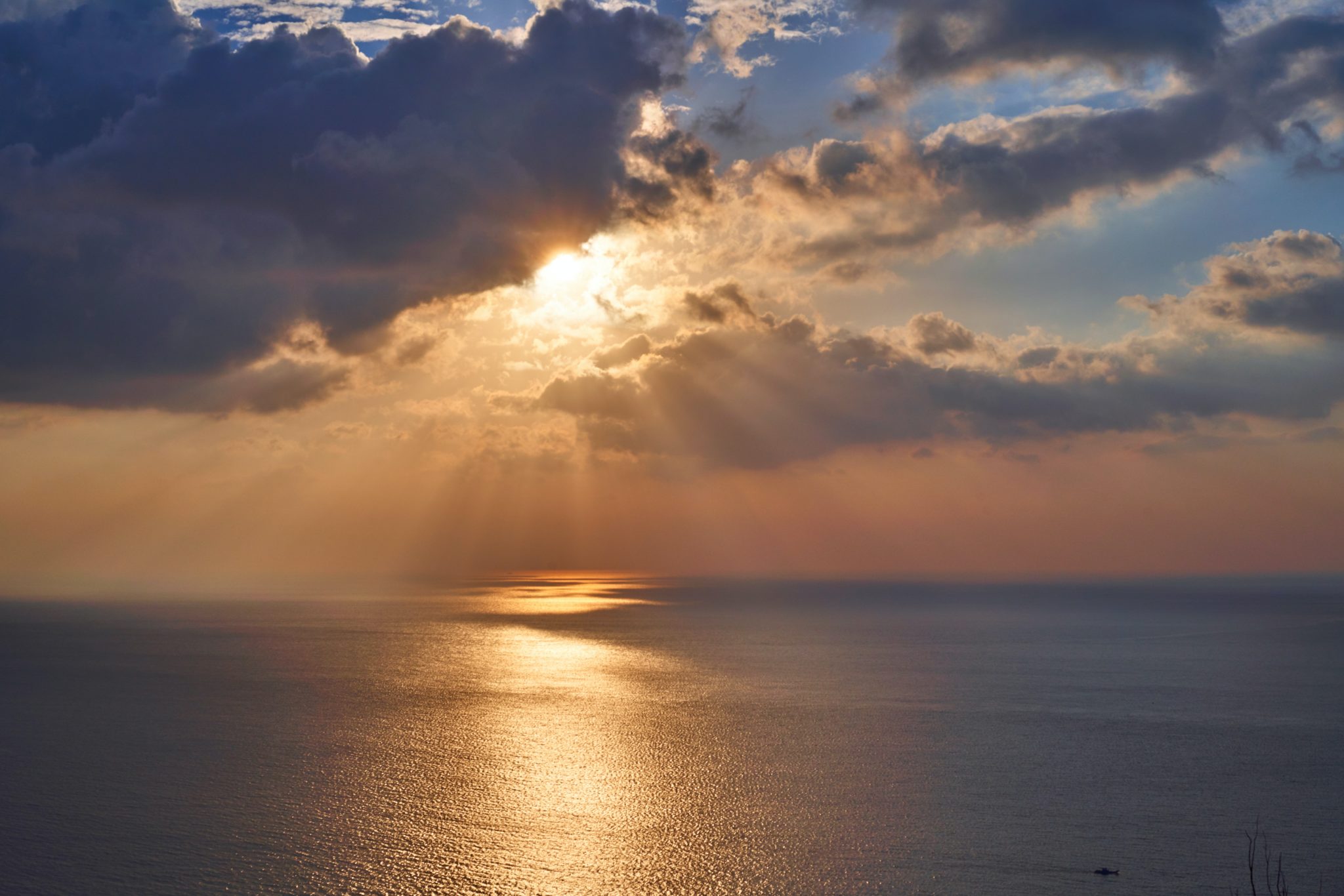 The sun shining through the clouds and ocean.