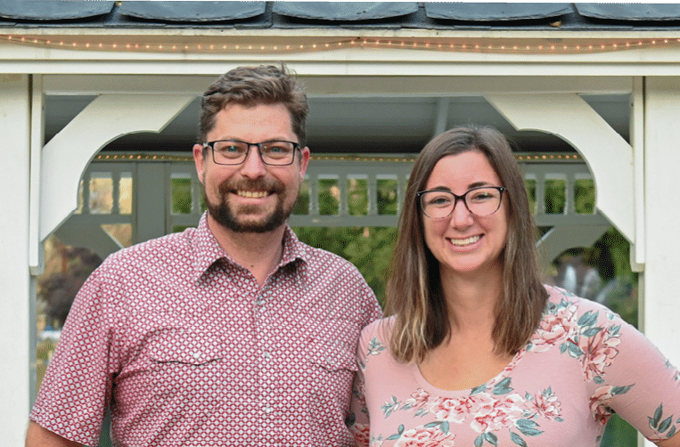 Nick and Danielle smiling at the camera in front of a gazebo.