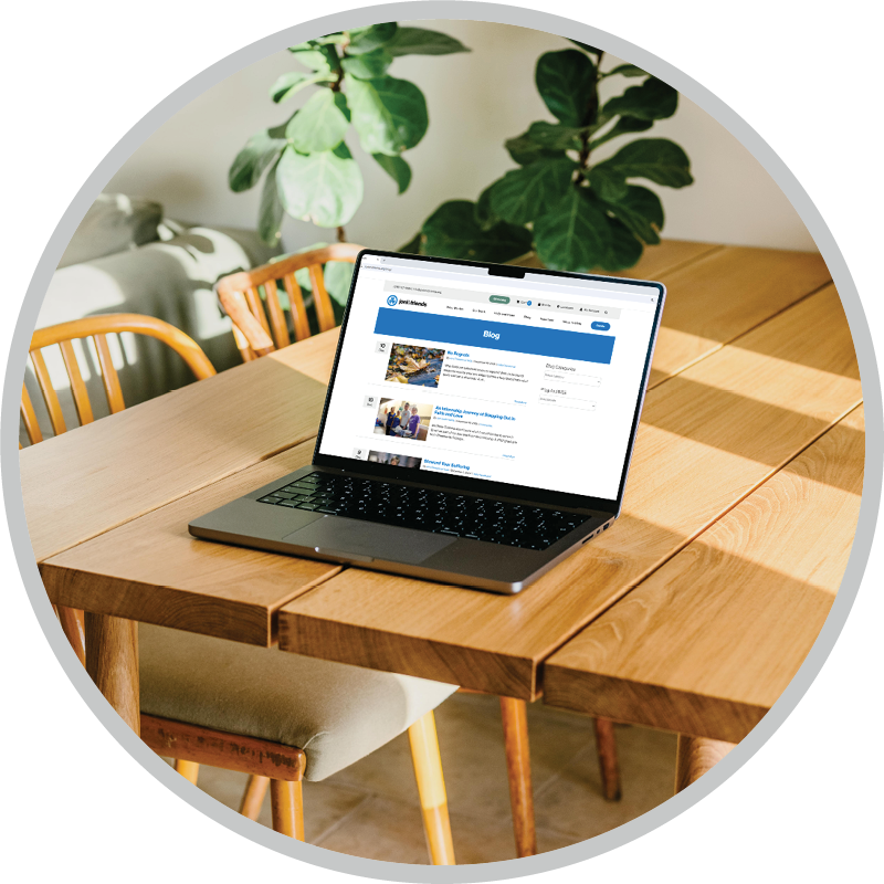 A laptop on a wooden table displaying the blogs of Joni and Friends, with the website visible on the screen.