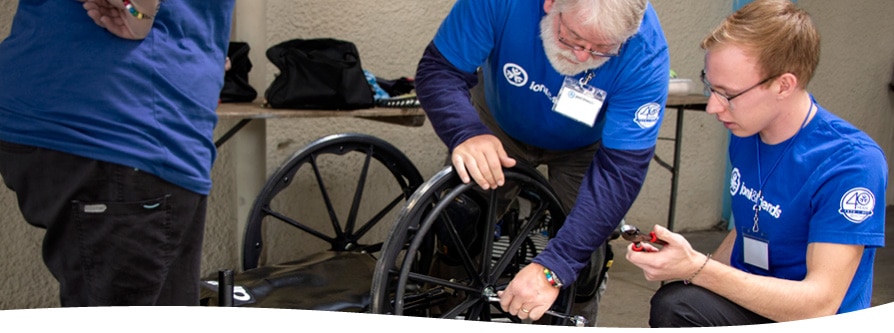 A volunteer repairs a wheelchair