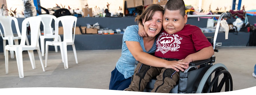 A mother embraces her child in his new wheelchair