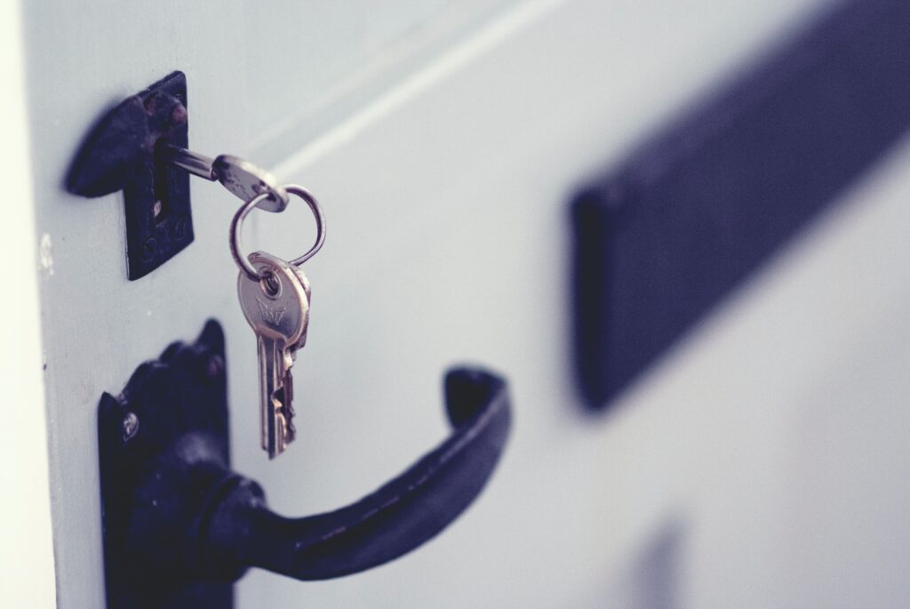 Close up of a key in a key-hole of a door with a door-handle below it.
