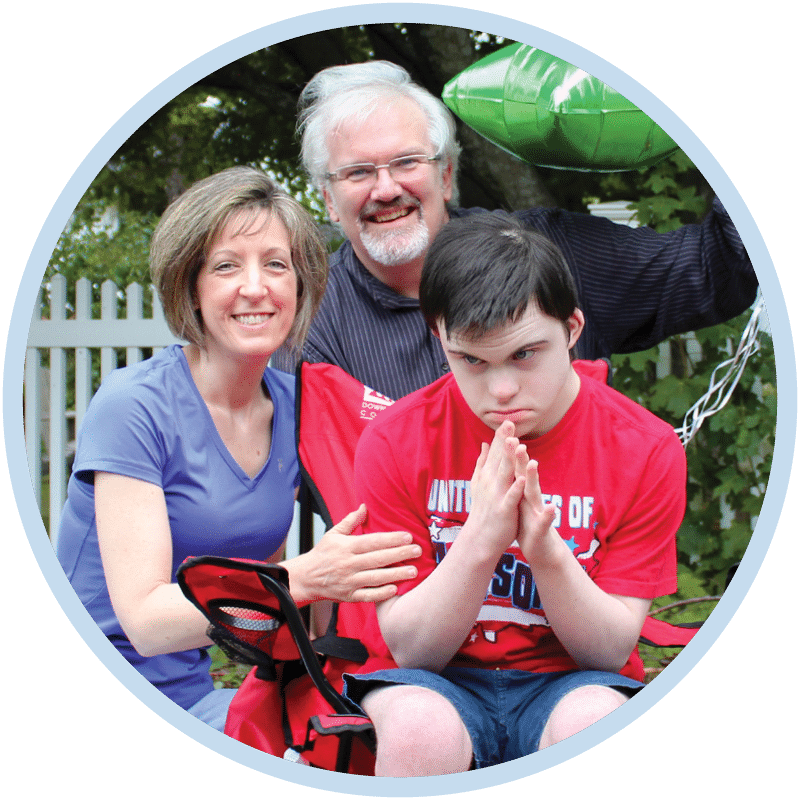 A woman, a man, and a boy in a wheelchair, all smiling for the camera.