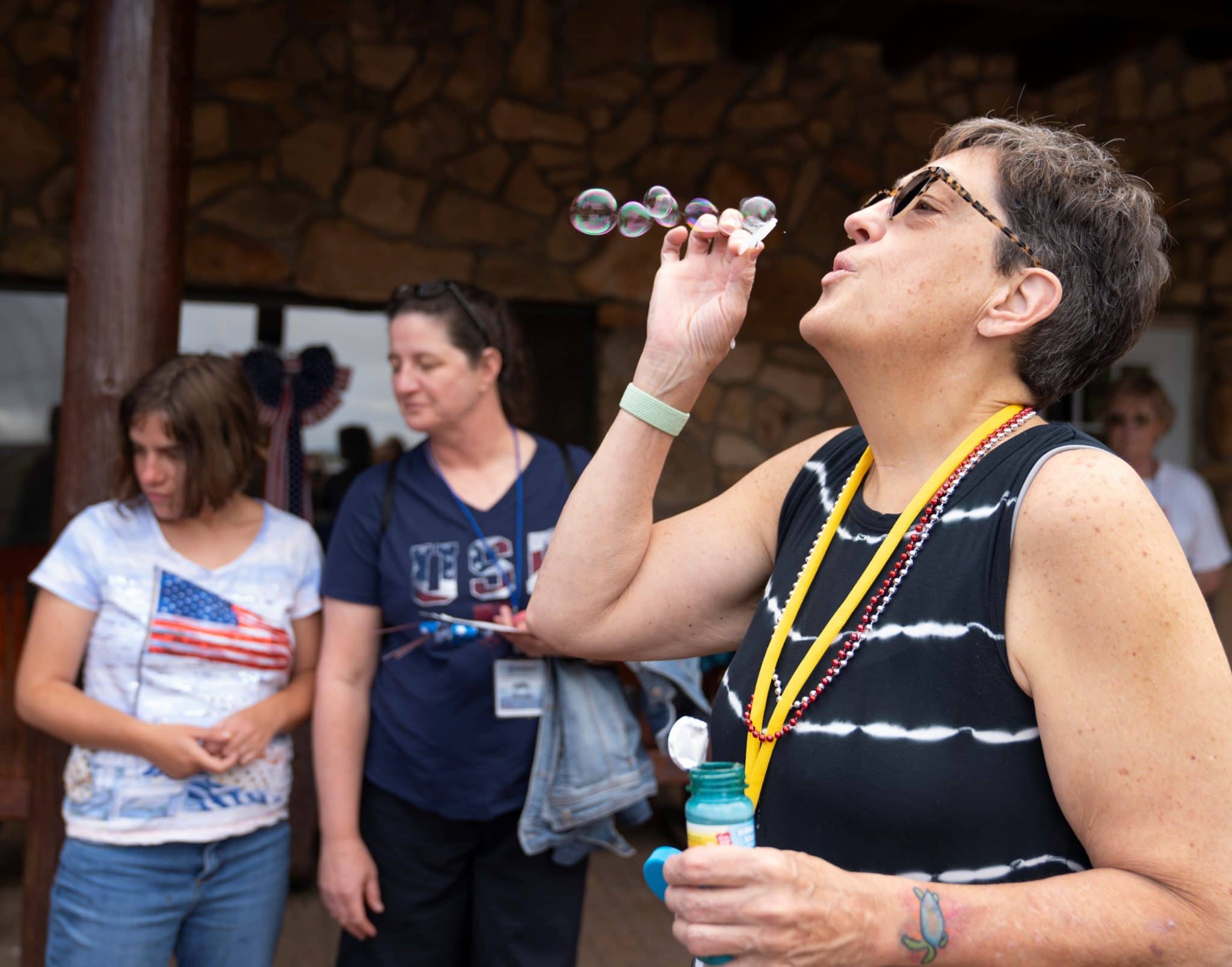 Grandma Julie blows bubbles as other Family Retreat attendees stand in the background. 