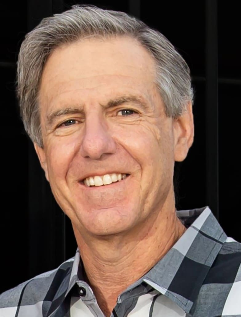 A close up portrait of Dr. Andy Laurie smiling against a dark background.