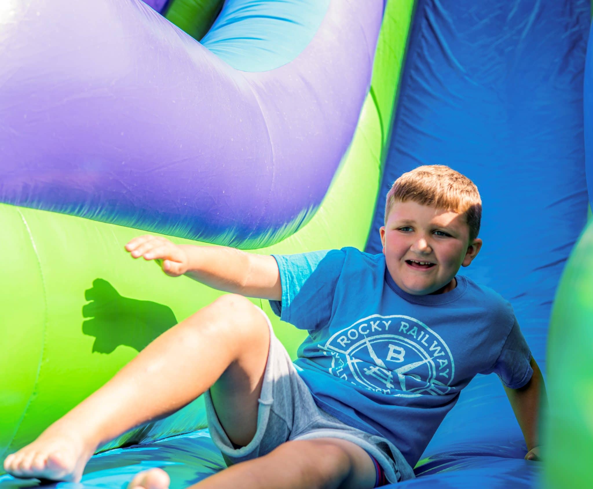 Kobe sliding down a brightly colored slide and smiling as he goes.