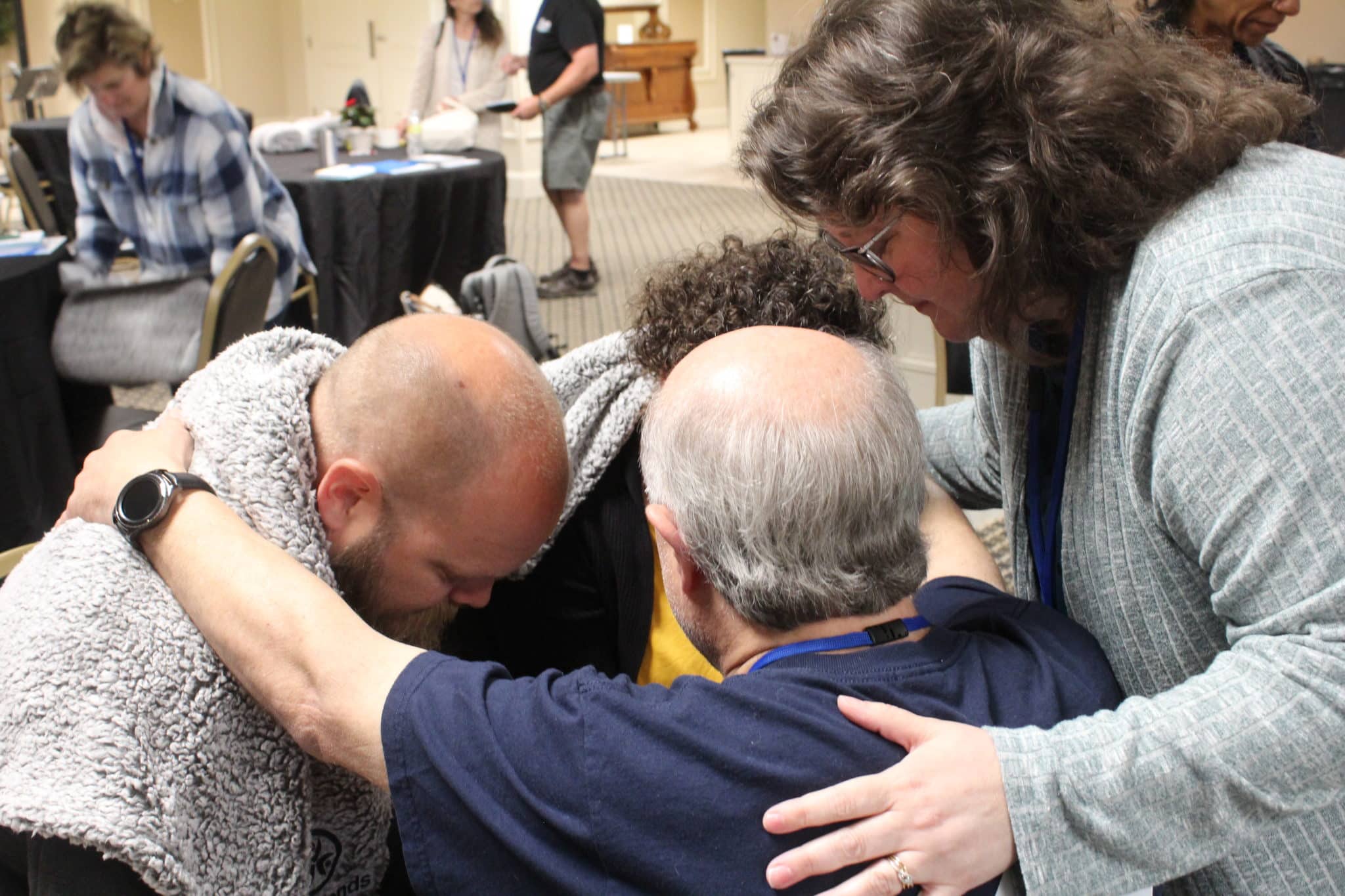 A close up of Chris and Julie being prayed over by another older-looking couple.