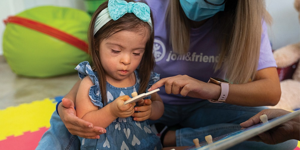 A girl and volunteer play with a puzzle