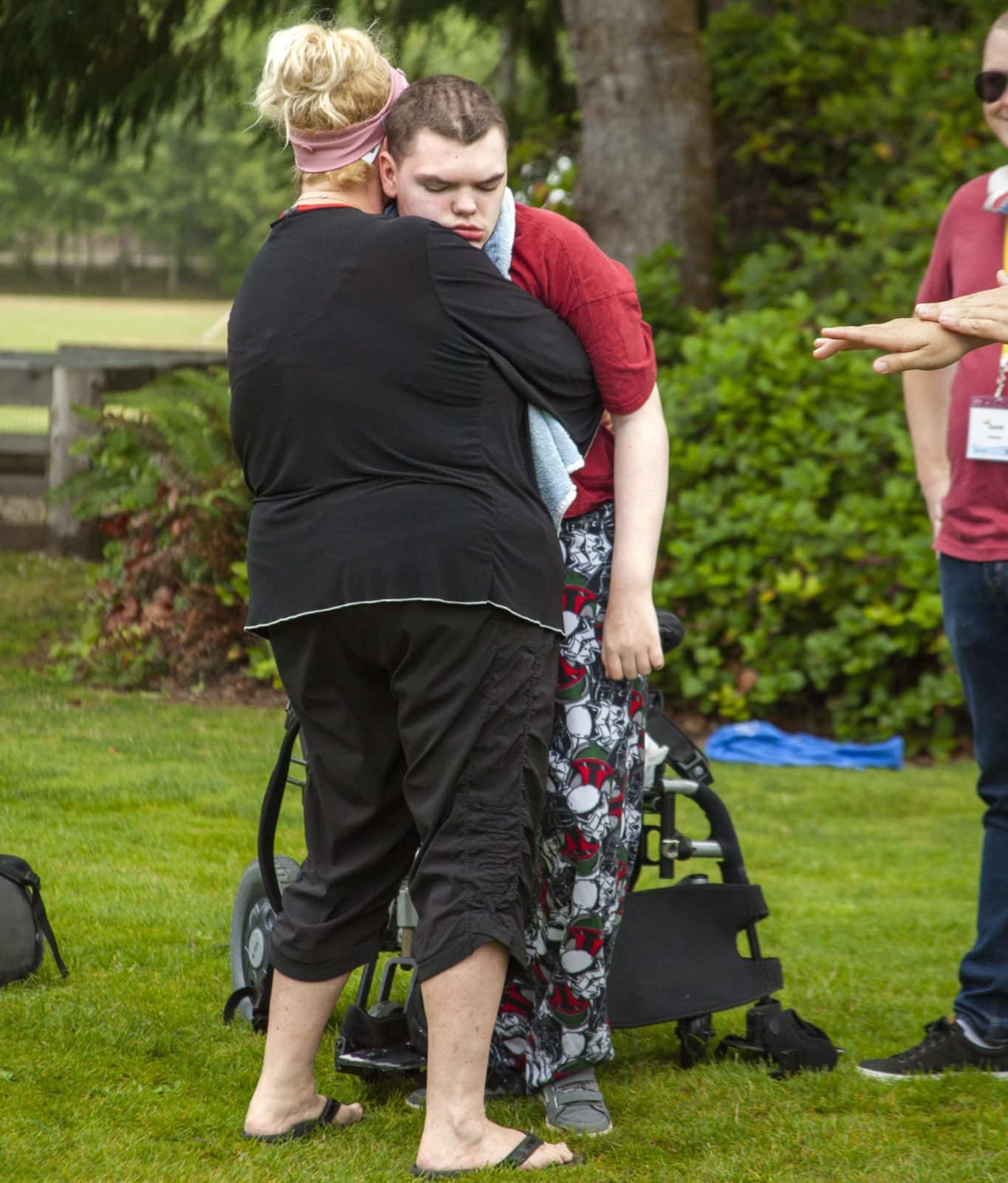 Shawna standing her son, Cody, up our of his wheelchair and embracing him.