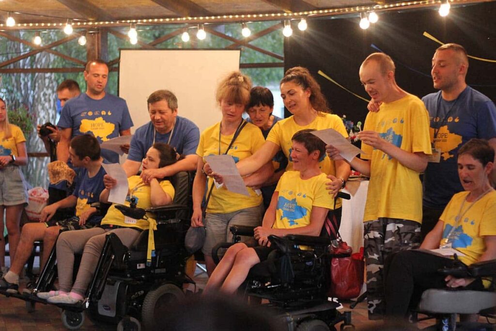 People of all abilities in yellow shirts, singing songs at International Family Retreat