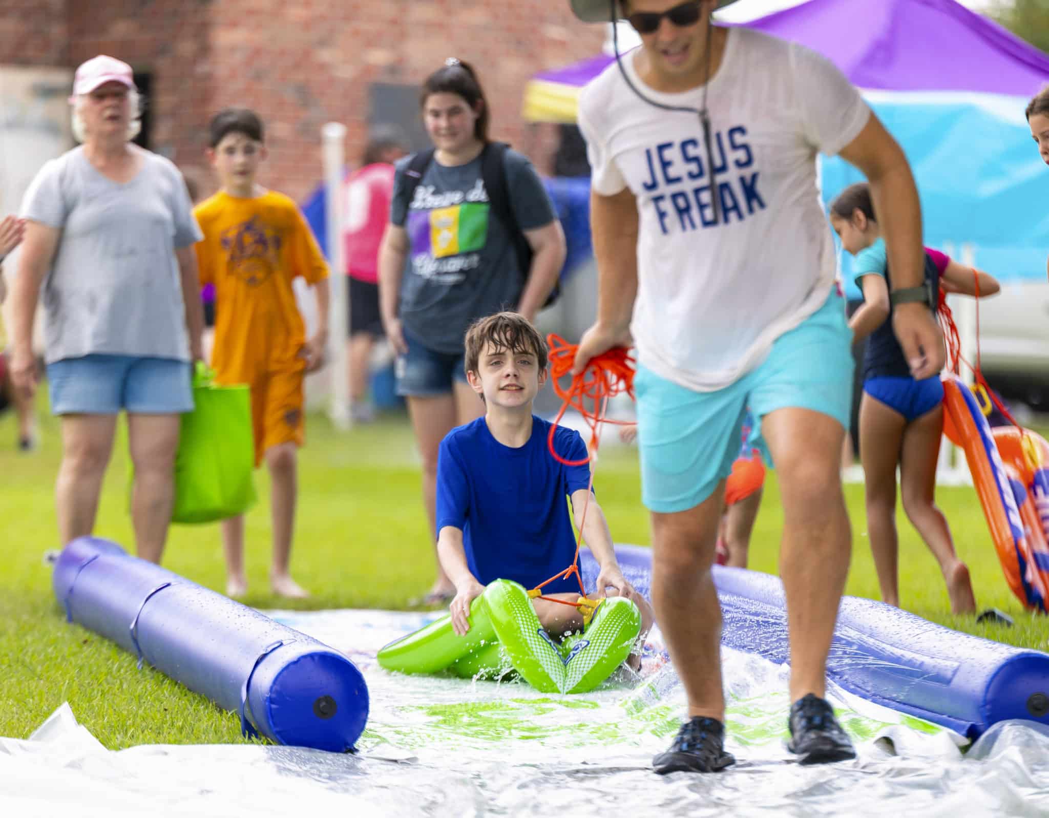 Robbie being pulled on a floaty down the slip and slide at Splash Day with Fellowship church.