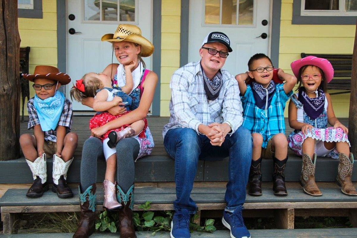 A group of six kids smiling at the camera, three of which appear to have a disability.