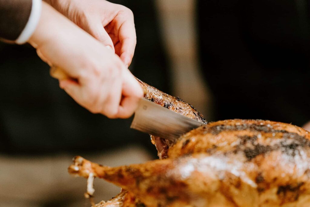 A man cutting a turkey with a large knife.