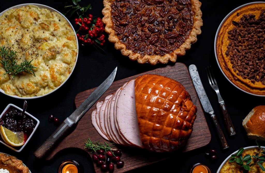 A close up of a ham, pecan pie and potatoes on a banquet table.
