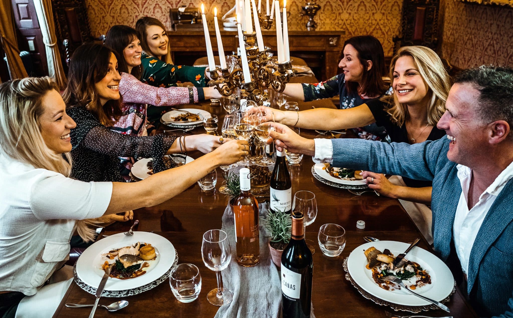 A scene of a group of people sitting around a table eating a meal and toasting.