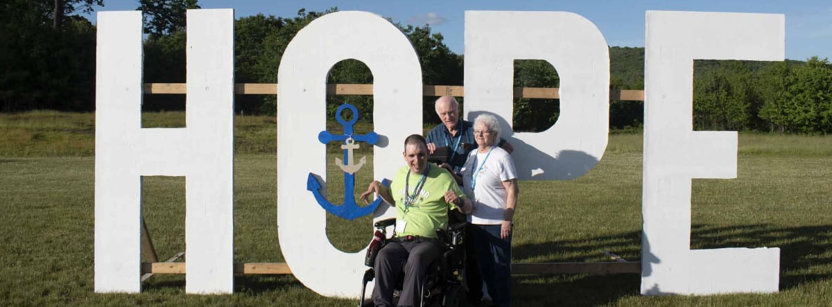 A family poses in front of a Hope sign at Family Retreat