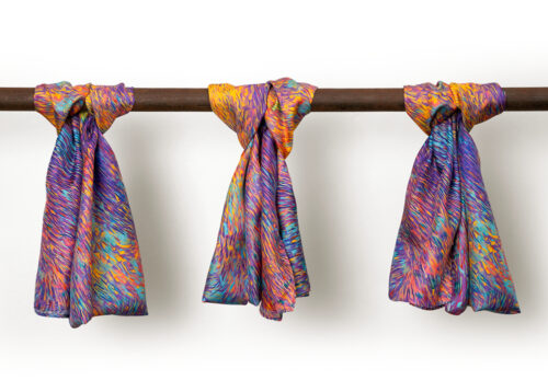 Three night sky silk scarves hanging on a pole