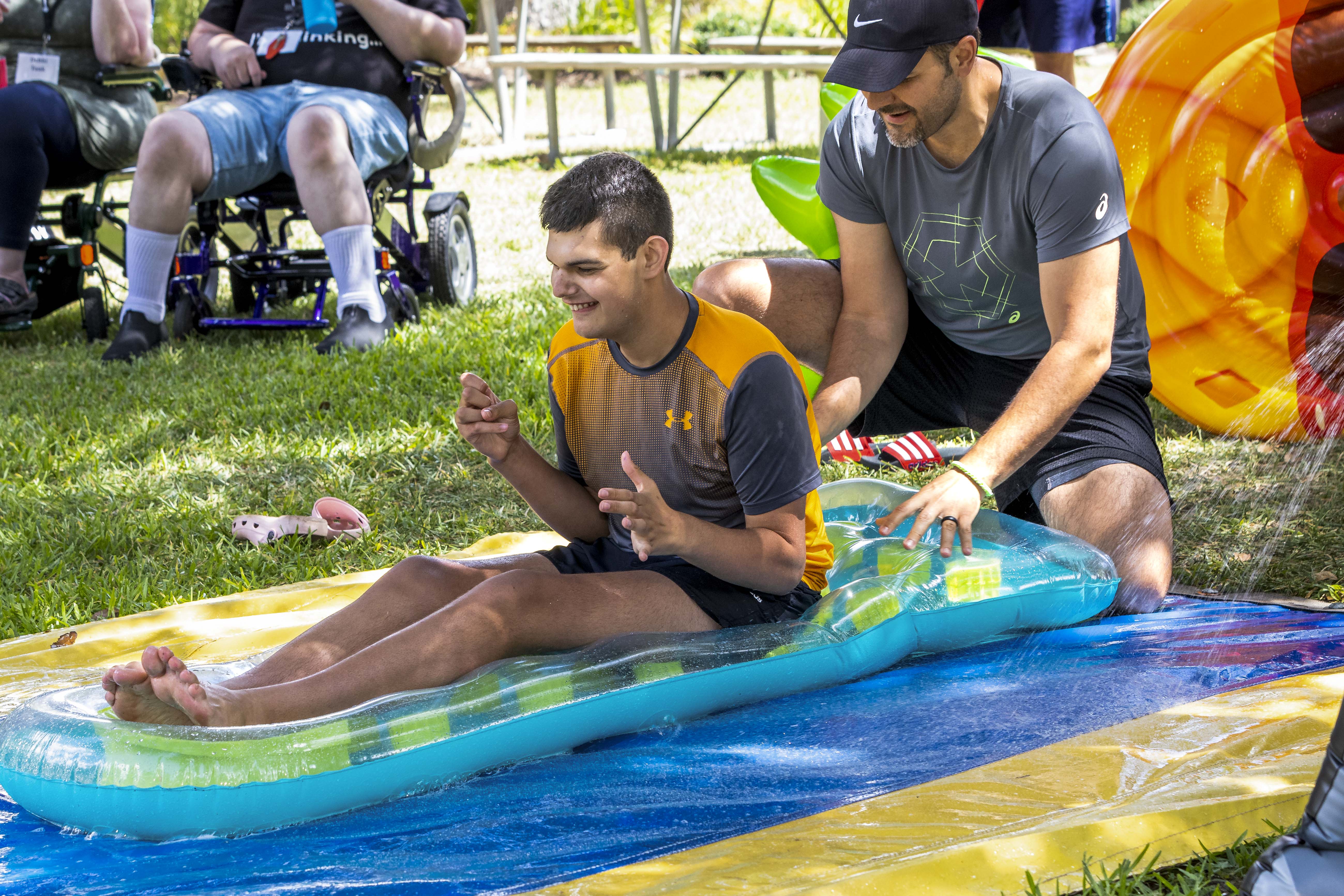 A picture of Isaac being pushed down a slip and slide by his father at family retreat.