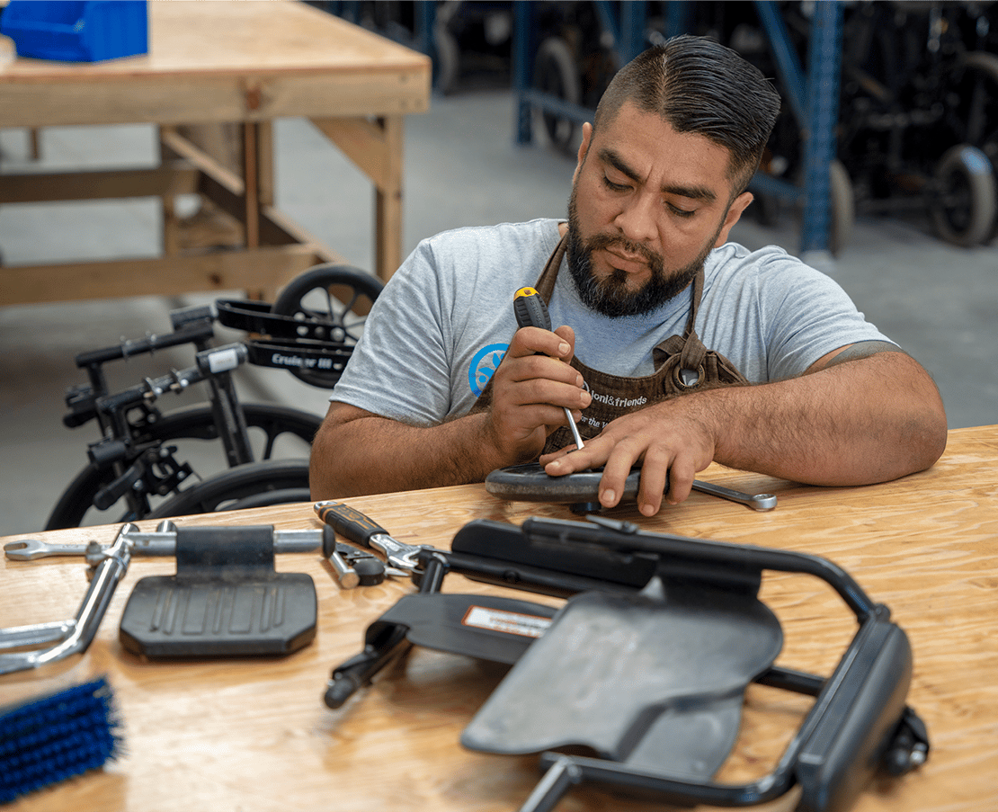 Sergio focusing on repairing a wheelchair inside the Restoration Center.