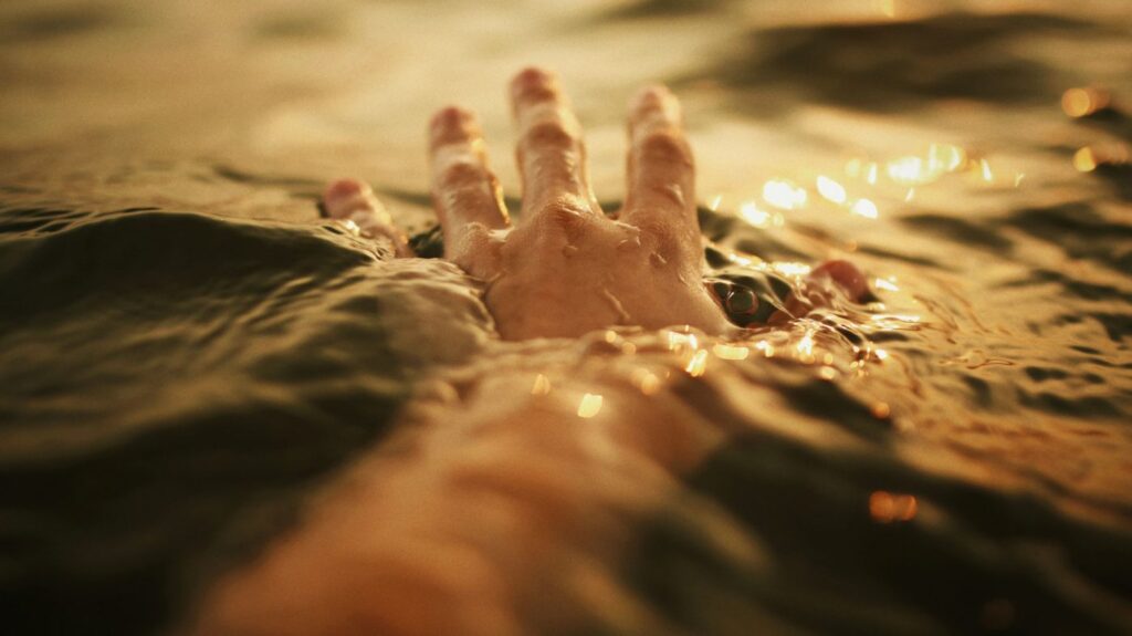 A hand coming out of stirred up water.