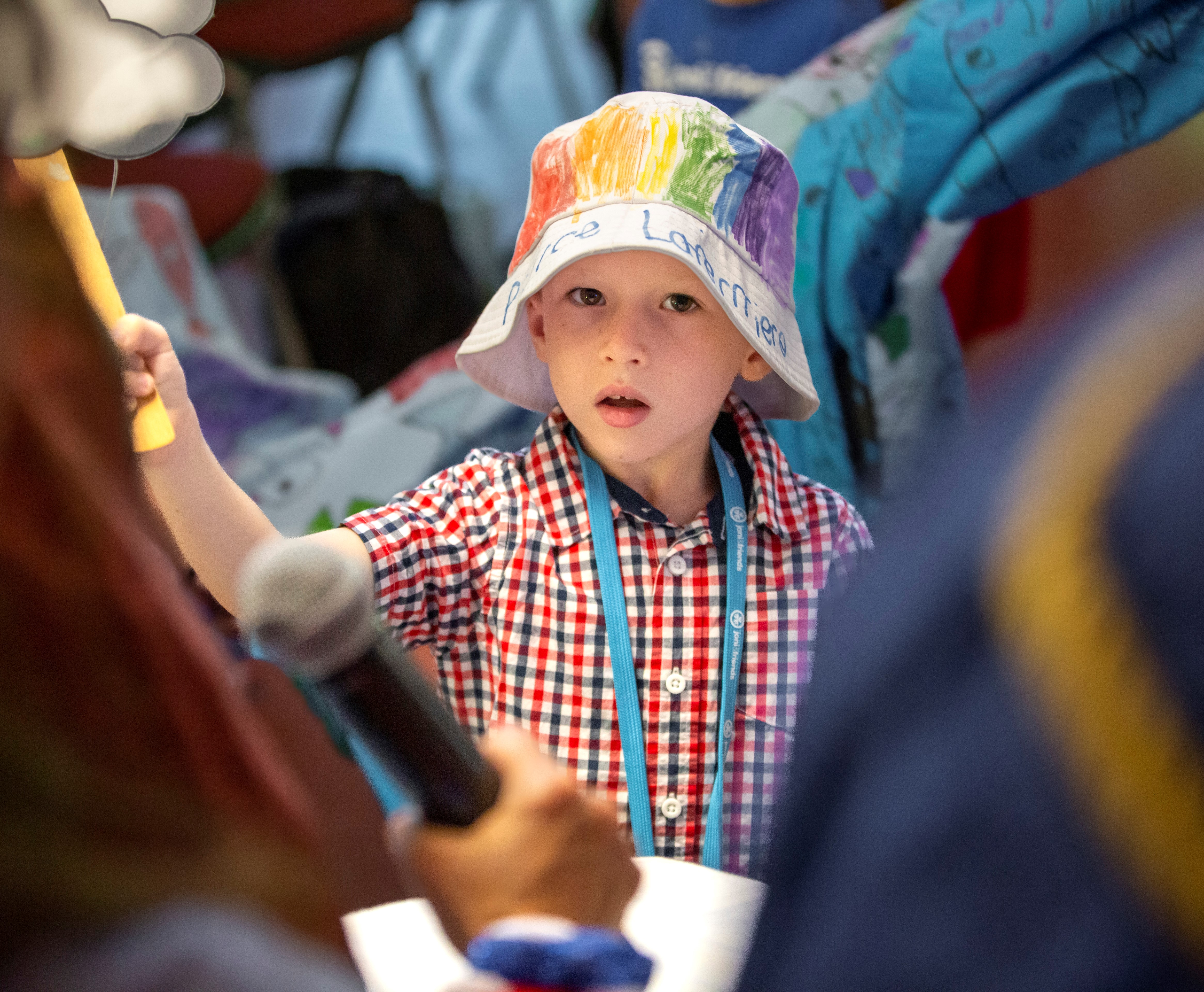 A little boy with a colorful bucket hat on looking at the camera.