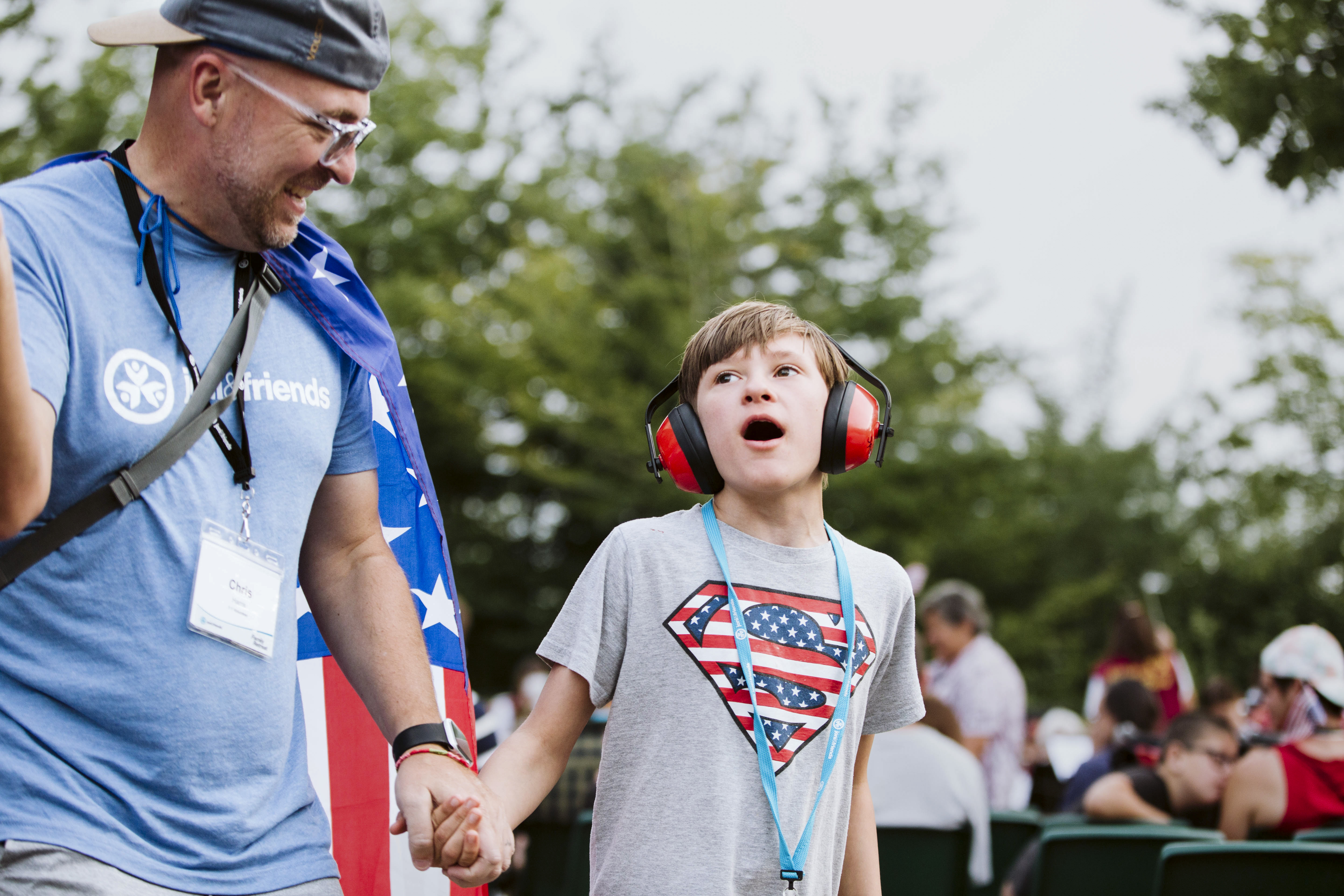 A young boy with headphones on smiling up at a Joni and friends volunteer.