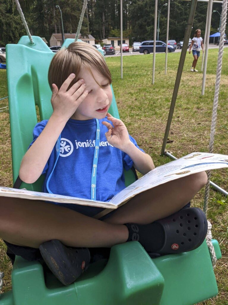 One of Sarah and Allen's boys reading a book in a swing at family retreat.
