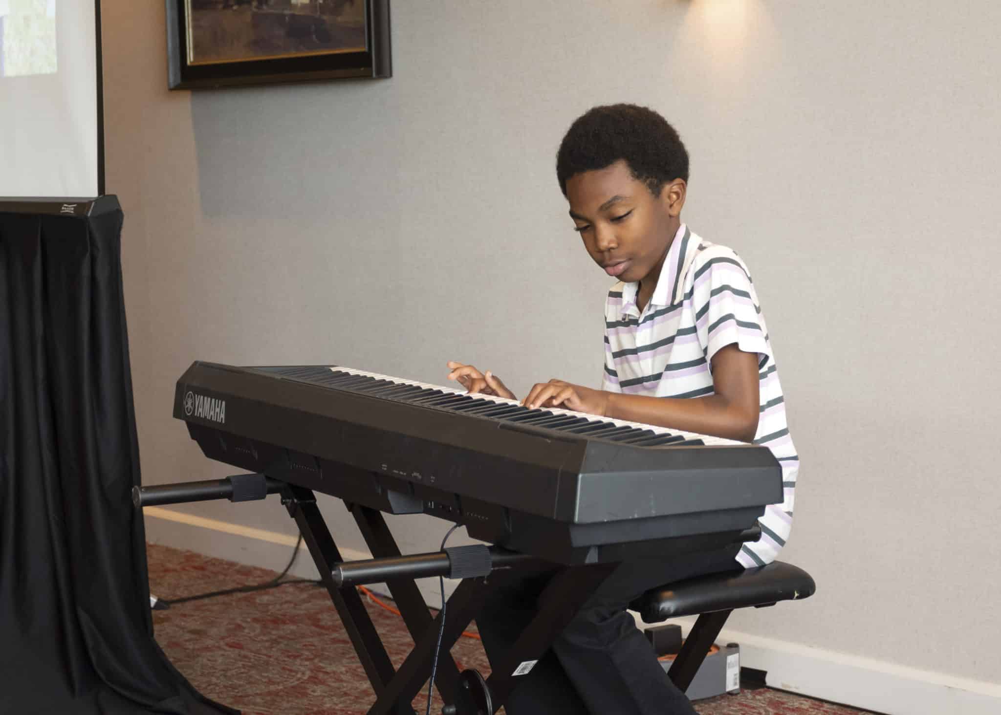 Matthew playing the keyboard and smiling.