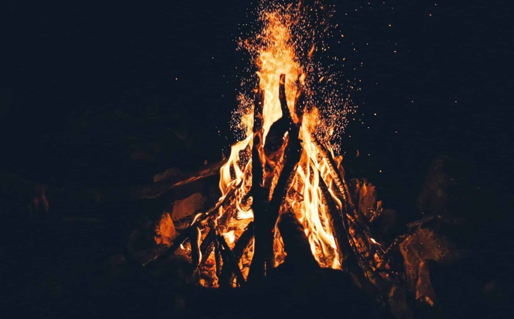 Close up of a campfire with sparks flying into the air.