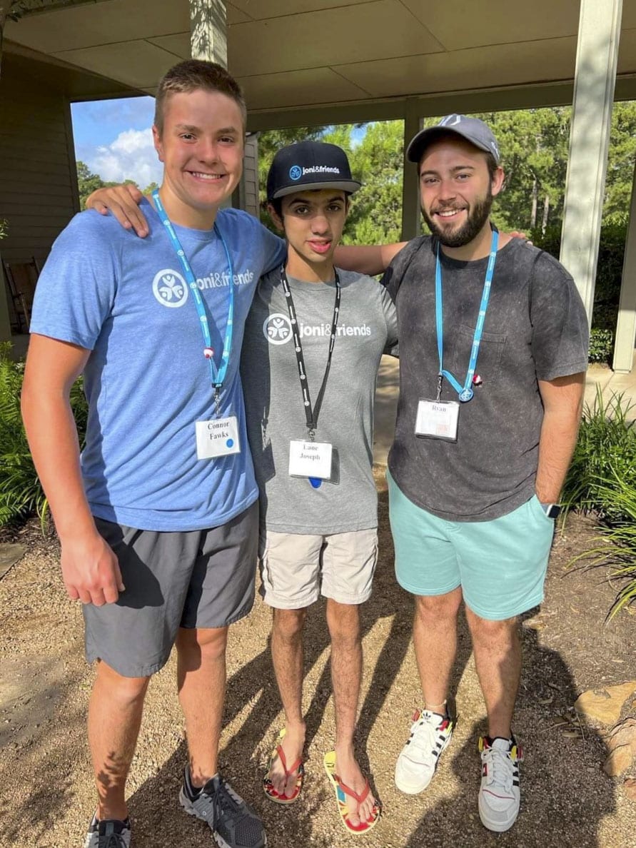 A picture of Lane with his two Joni and Friends buddies on either side of him, all smiling at the camera.