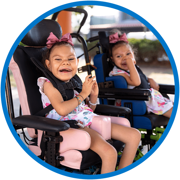 Two girls smiling in their wheelchairs