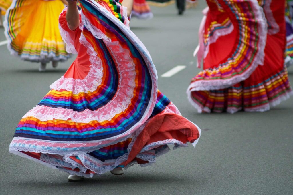 Women dancing in the street with Spanish-style skirts on, twirling them around.