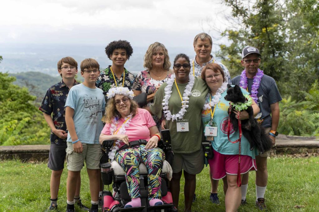 A group photo of a family with children with disabilities posing together in front of a mountain view in Tennessee.