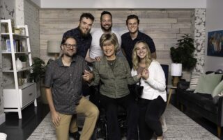 A group photo of Joni and Friends staff posing around Founder and CEO, Joni Eareckson Tada.