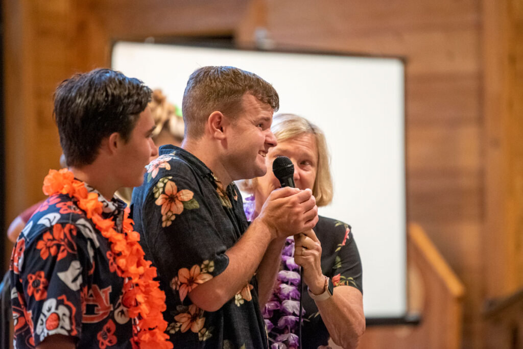 Charlotte Hoffman holding a microphone up to a young man at Family Retreat who has a disability.