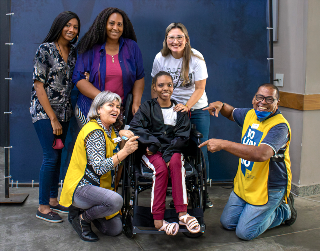 A group picture of Larissa in her new wheelchair, with three Joni and Friends volunteers and her mother and sister, all smiling at the camera.