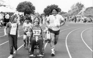 Joni and Ken on a track racing with a group of kids. All smiling at the camera.