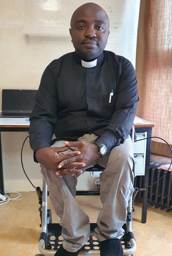 A portrait of Dr. Daniel Kyungu Tchikala seated in his wheelchair and dressed in his clergy shirt.