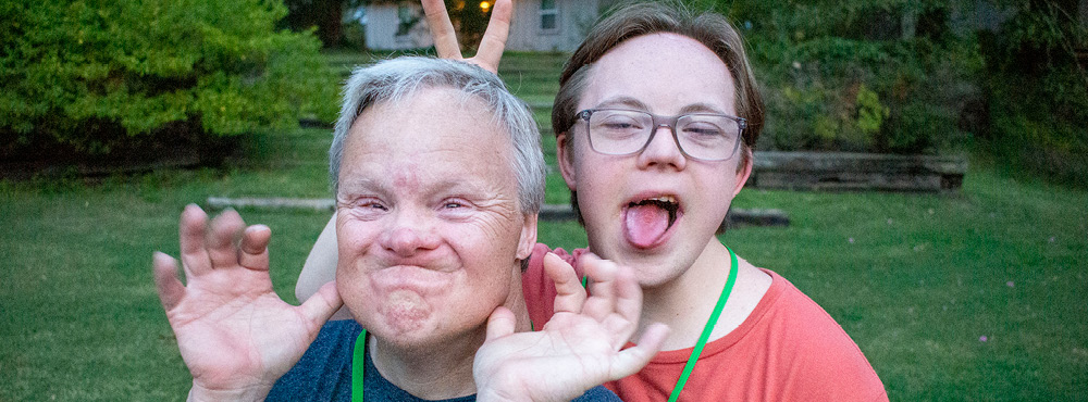 A volunteer and camper make funny faces. They are having a ton of fun at Family Retreat!