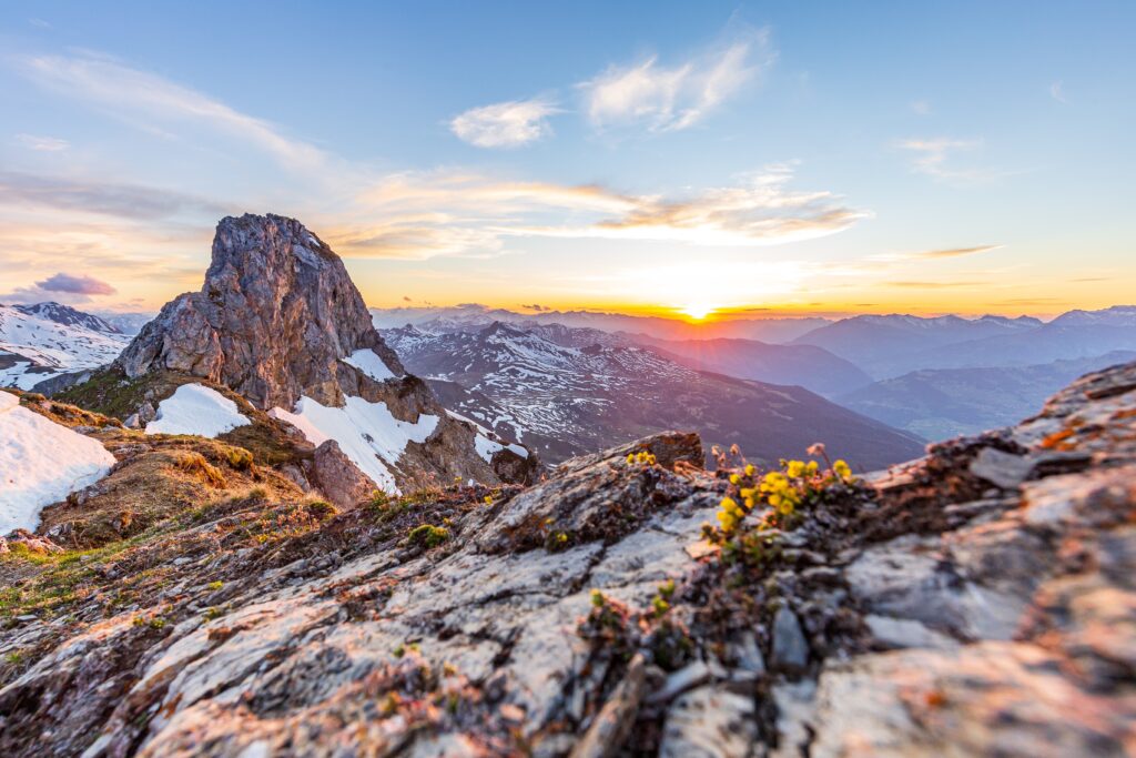 The view of a gorgeous mountain range with the sun rising over the horizon, snow covering some of the peaks.