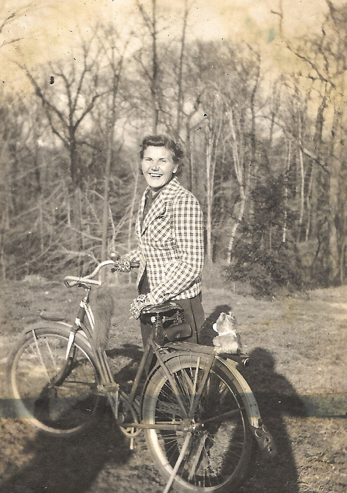 Joni's mother posing for a photo with a bicycle
