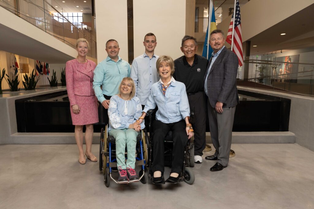 Joni, Ken, Steve Bundy, Laura Gardner and the three people visiting from Ukraine to present the award the ministry standing in front of the floating chapel at the Joni and Friends International Disability Center and smiling at the camera.