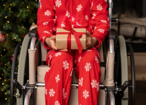 A child in a pediatric wheelchair holding a gift