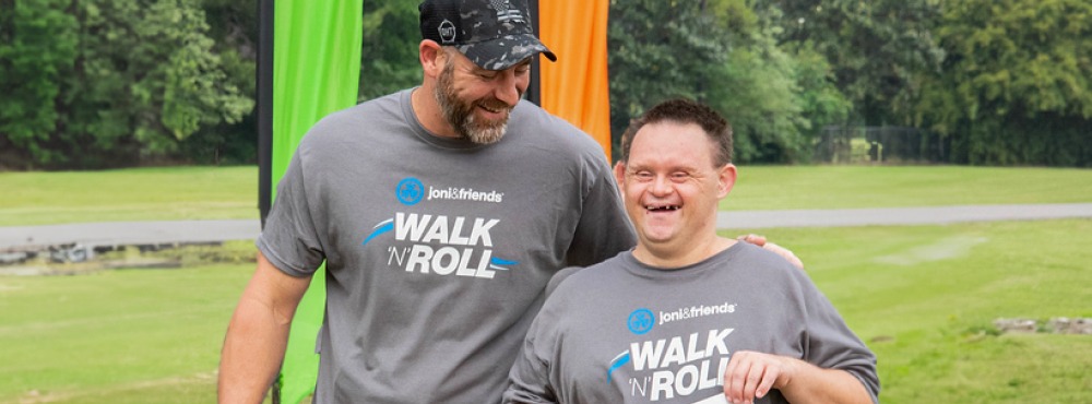 A volunteer and smiling participant are having a great time at walk 'n' roll.