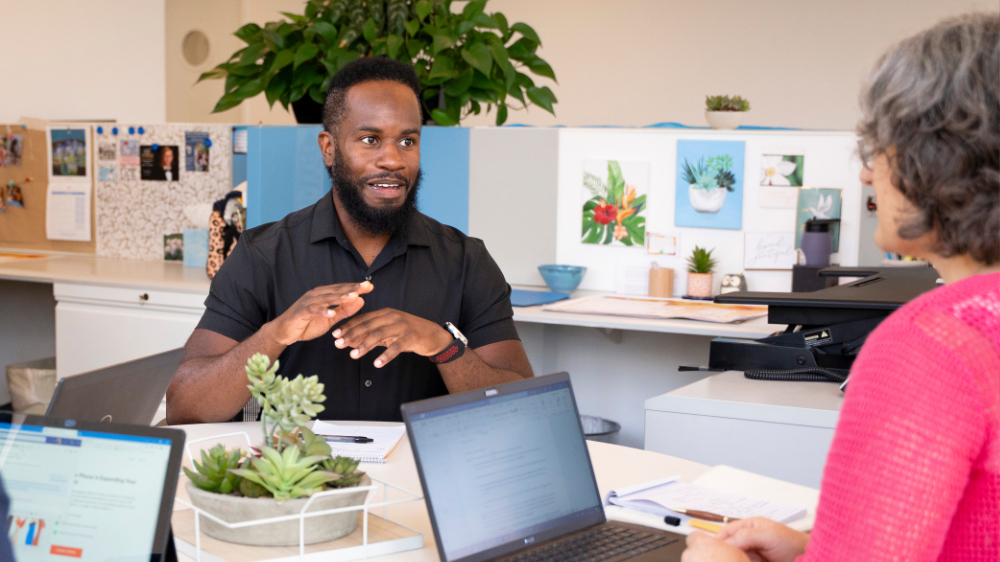 A man is talking to a woman in an office.