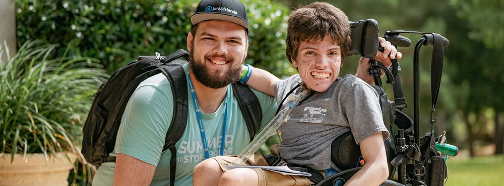 A volunteer and camper pose for a photo at Family Retreat