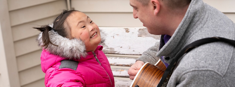 A man playing guitar with a little girl.