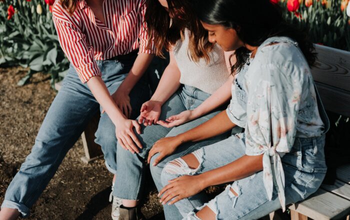 A picture of three girls praying over their friend together.