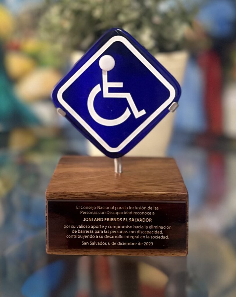 A picture of the award given to Joni and Friends. It shows a small wooden base with a plaque on it and the universal sign for disability above it.