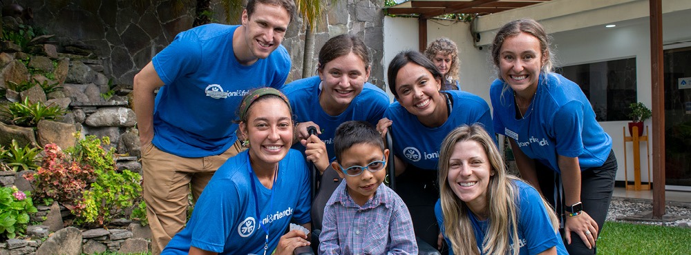 A group of interns pose for a photo with a boy in his wheelchair